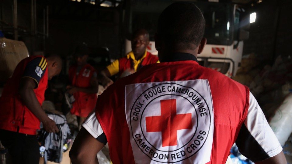 a person stands with their back to the camera wearing a Cameroon Red Cross vest