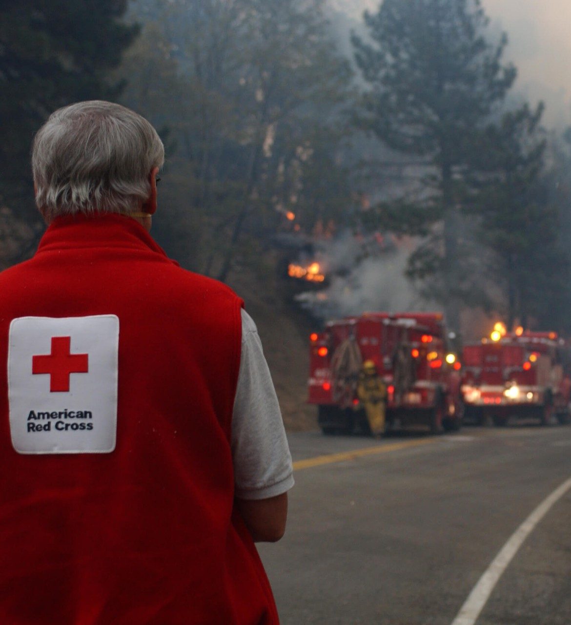 red cross volunteer watching firefighters fight a widlfire